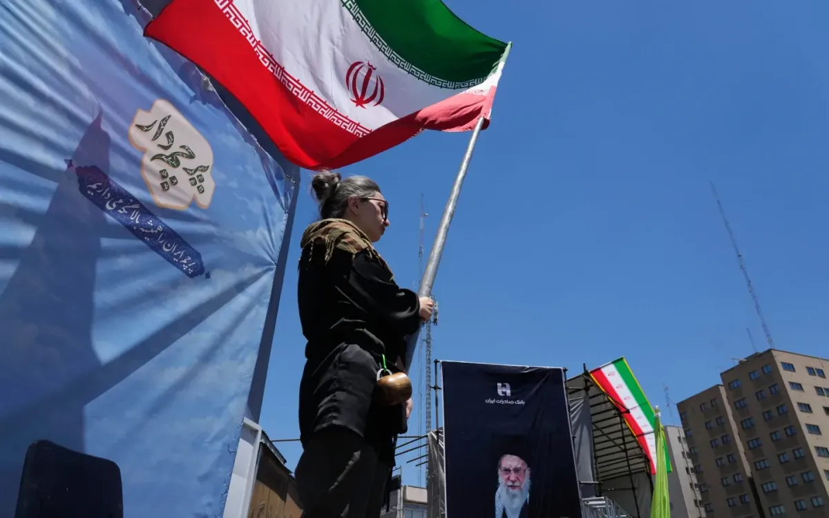 Một phụ nữ vẫy cờ Iran bên chân dung cố Lãnh tụ tối cao Ali Khamenei tại Tehran, ngày 15/6/2026. (Ảnh: AP)