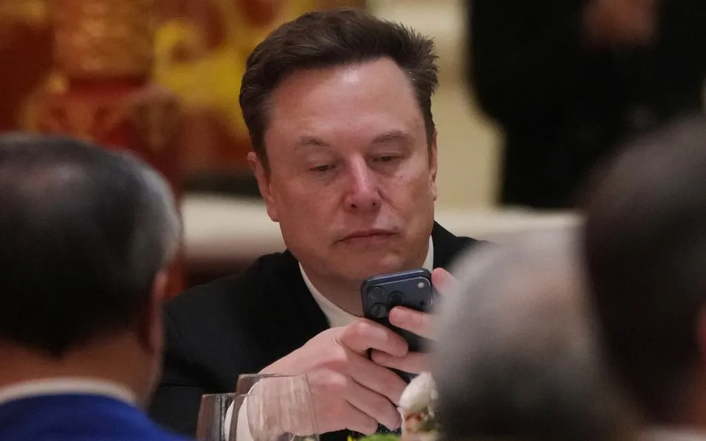 Elon Musk sử dụng điện thoại tại quốc yến ở Bắc Kinh ngày 14/5/2026. (Ảnh: AP)