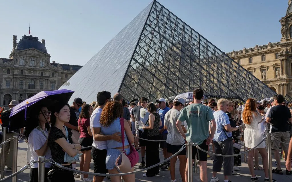 Du khách tham quan bảo tàng Louvre giữa trời nắng nóng gay gắt, ngày 24/6/2026. (Ảnh: AP)