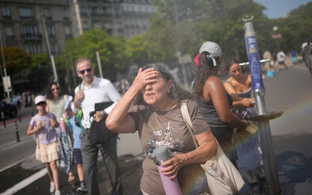 Du khách giải nhiệt tại vòi phun nước công cộng ở Paris, Pháp, ngày 26/6/2026. (Ảnh: AP)