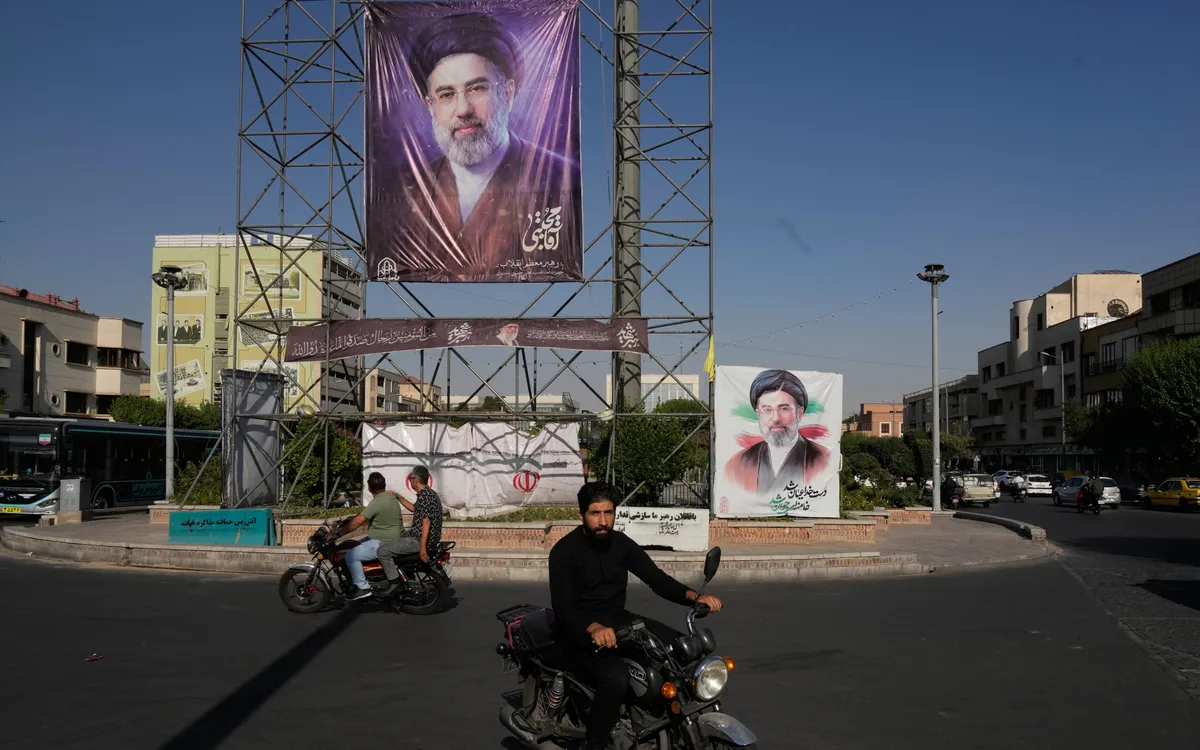 Người dân đi xe máy ngang qua biểu ngữ có hình chân dung Lãnh tụ tối cao Iran Mojtaba Khamenei, ở trung tâm Tehran, Iran, ngày 29/6/2026 (Ảnh: AP)