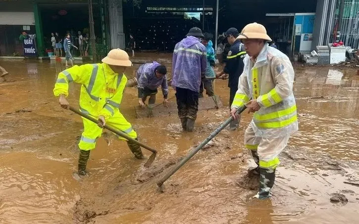 Lực lượng Cảnh sát giao thông, Công an Sơn La nạo bùn, khơi thông cống rãnh do mưa lớn kéo dài xảy ra tại xã Mường La. (Ảnh: TTXVN)