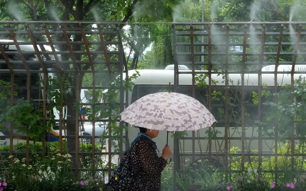 Một phụ nữ đi qua hệ thống phun sương làm mát tại Seoul, Hàn Quốc. (Ảnh: AP)