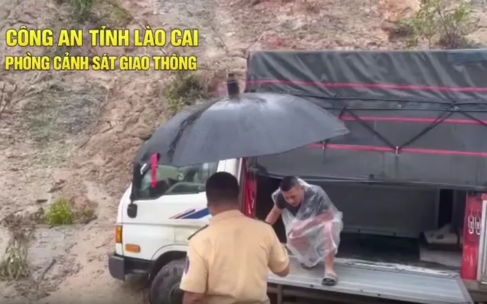 Lực lượng CSGT và Công an xã phối hợp đưa 2 tài xế khỏi điểm sạt lở nguy hiểm (Ảnh chụp màn hình)