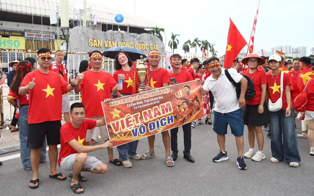 Hội cổ động viên từ Khánh Hòa vượt chặng đường xa, mang theo cúp mô hình cùng băng rôn "Việt Nam vô địch" check-in trước cổng sân vận động Quốc gia Mỹ Đình.