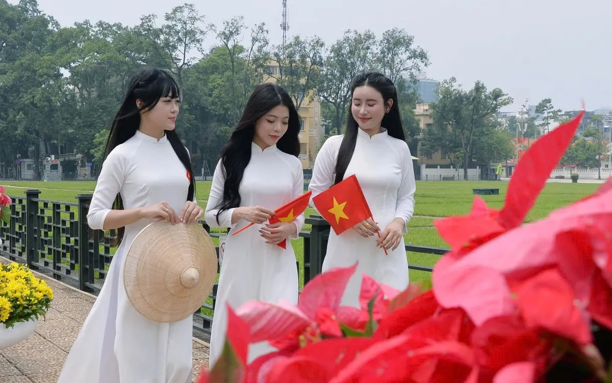 Nhóm bạn trẻ duyên dáng trong tà áo dài trắng cùng nón lá và cờ đỏ sao vàng.