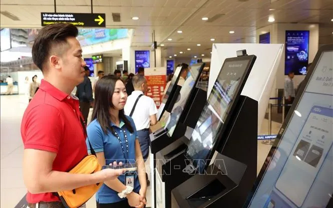 Nhân viên sân bay Nội Bài hỗ trợ hành khách làm thủ tục qua hình thức quét sinh trắc học để giảm thiểu thời gian xếp hàng chờ đến lượt tại quầy, sáng 28/8/2026. Ảnh: Quốc Khánh/TTXVN