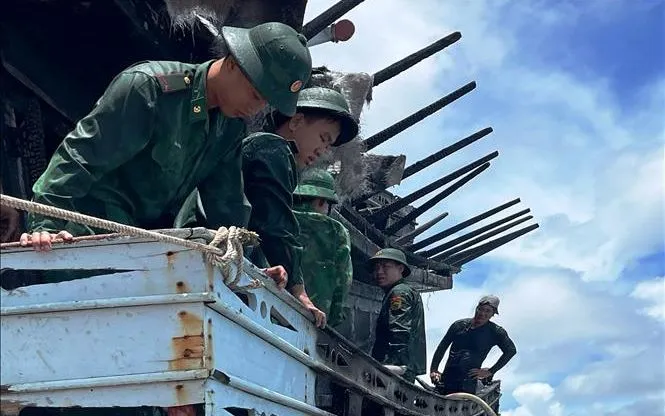 Bộ đội Biên phòng Cà Mau hỗ trợ ngăn chặn đám cháy trên tàu cá tại Sông Đốc. Ảnh: TTXVN 

