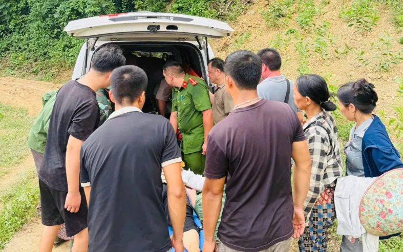  Cán bộ, chiến sĩ Công an xã Điềm He hỗ trợ đưa người bị nạn lên xe cứu thương. Nguồn: Bộ Công an