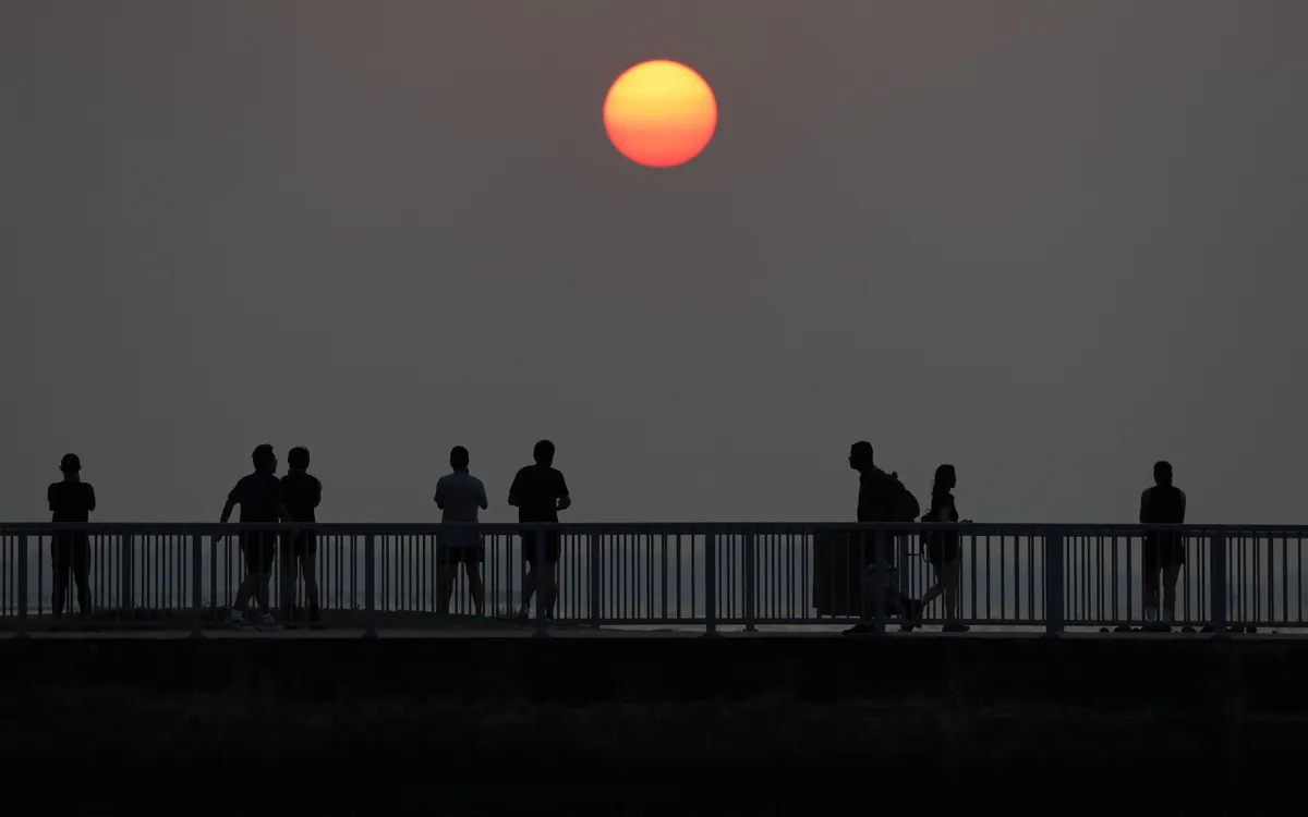 Người dân ngắm bình minh dọc bờ biển phía đông Singapore, ngày 23/8/2026. (Ảnh: Reuters)