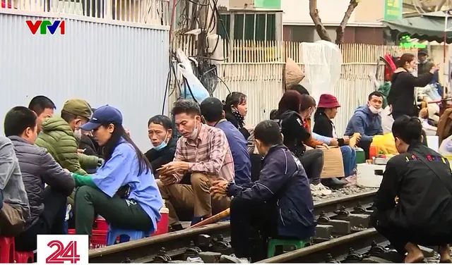 Vô tư bán hàng, ăn uống bên đường ray tàu hỏa trước Bệnh viện Bạch Mai - Ảnh 1.