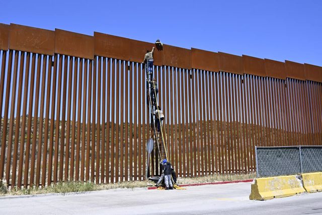 Người di cư bắc thang vượt qua hàng rào biên giới Mỹ - Mexico - Ảnh 1.