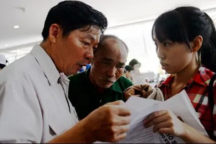 Le Tuan Anh (C), 60, and his daughter listen to guildance from a supervising teacher before taking the national high school exam (photo: Tuoi Tre)