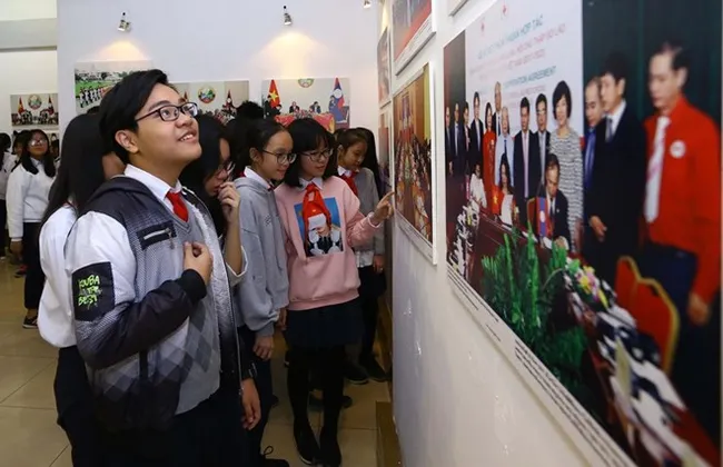 Students in Hanoi look at the photos of the exhibition (Photo: VNA)