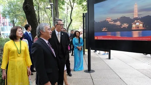 Visitors admiring photos on display at the exhibition (Photo: VNA)