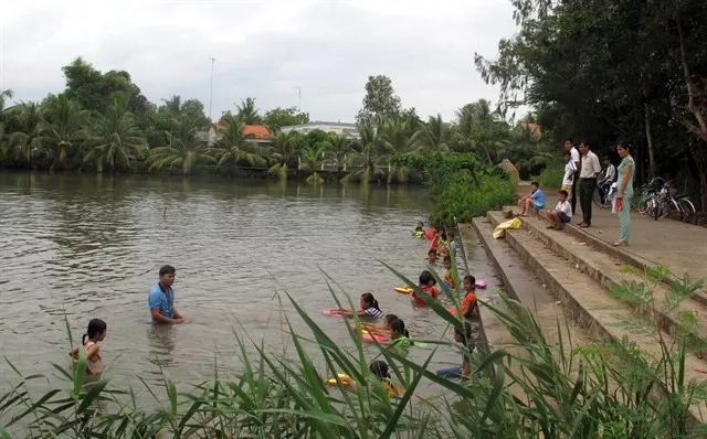 A teacher in the Mekong Delta province of Ben Tre's My Chanh commune teaches children how to swim in a local lake (Photo: VNA)