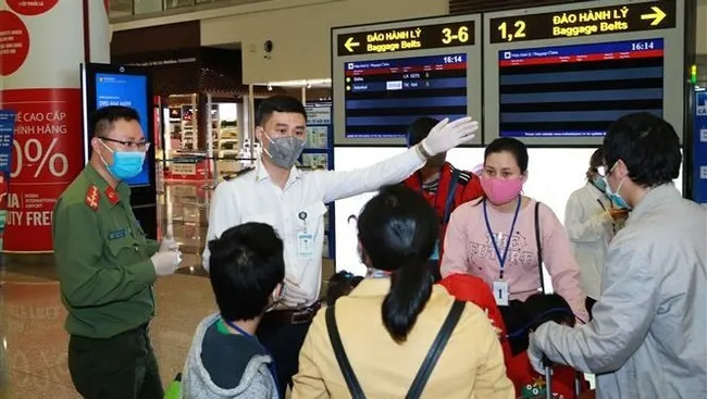 Airport border gate police guide passengers to isolation area. (Photo: VNA)