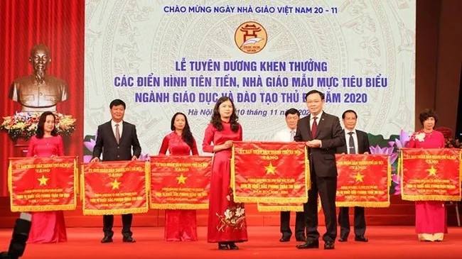 Politburo member and Secretary of the Hanoi Party Committee Vuong Dinh Hue presents the emulation flag to outstanding units in the capital city’s education sector. (Photo: NDO/Quy Tung)