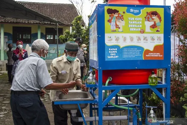 Residents wash their hands before giving their votes in the regional head elections in an evacuation camp in Yogyakarta (Photo: Antara)