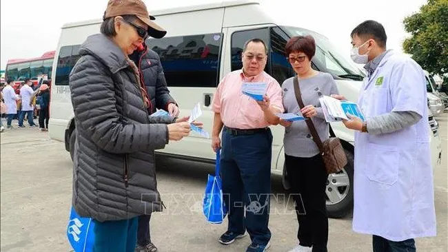 A medical worker delivers leaflets on Covid-19 for visitors to Ha Long Bay, Quang Ninh Province (Photo: VNA)