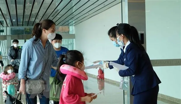 Passengers at Cam Ranh Airport receive leaflets guiding COVID-19 prevention. (Photo: VNA)
