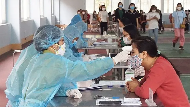 A health worker checks the body temperature of a resident in medical isolation at the Military School of Quang Ninh Province.