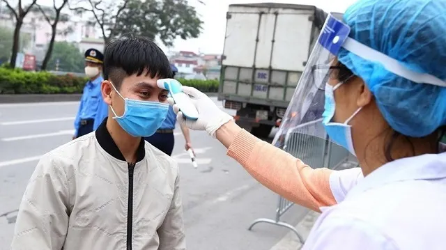 Checking body temperature of a driver. (Photo: VNA)