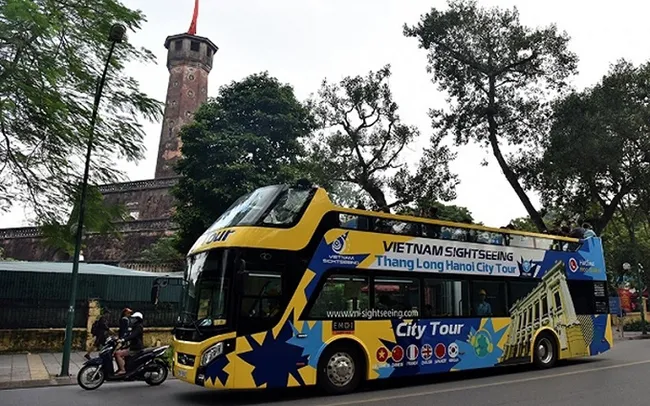 An open-top double-decker bus passes the Vietnam Military History Museum in Hanoi. (Photo: NDO/Duy Linh)