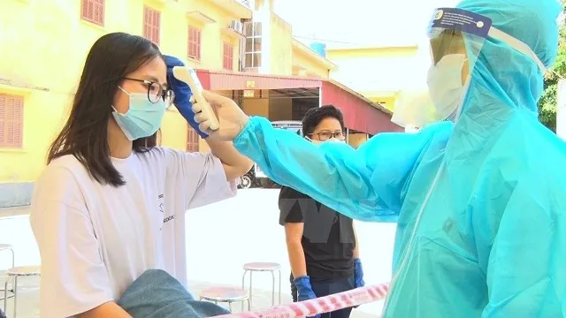 A medical worker checks body temperature for Vietnamese citizens. (Photo: VNA)