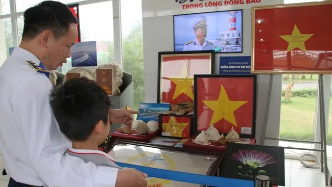 A naval soldier and his son admiring works on display at the exhibition. (Photo: Vietnam National Village for Ethnic Culture and Tourism)