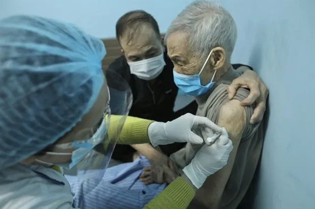An elderly man in Hanoi is vaccinated against COVID-19 at home. Vaccination coverage is one of the criteria for the assessment of pandemic risk level s. (Photo: VNA)