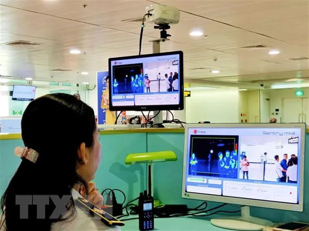A health worker checks the body temperature of foreign passengers at Tan Son Nhat Airport in Ho Chi Minh City . (Photo: VNA)