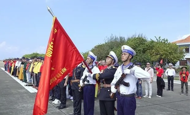 Delegates attend a flag hoisting ceremony in the Truong Sa island district (Photo: VNA)