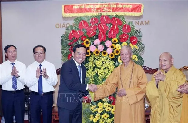 Deputy Prime Minister Tran Luu Quang presents flowers to Most Venerable Thich Tri Quang, Supreme Patriarch of the VBS Patronage Council (Photo: VNA)
