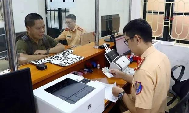 A vehicle owner applies for an administrative procedure on the granting of vehicle's number plate at the Traffic Police Department of Hanoi Police. (Photo: VNA)