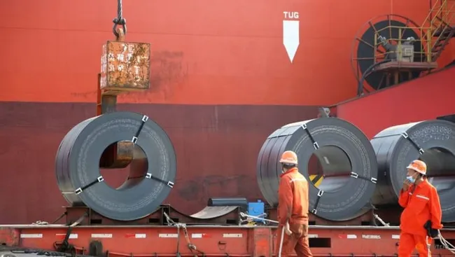 Workers outbreak load steel products for export to a cargo ship at a port in Lianyungang, Jiangsu province, China