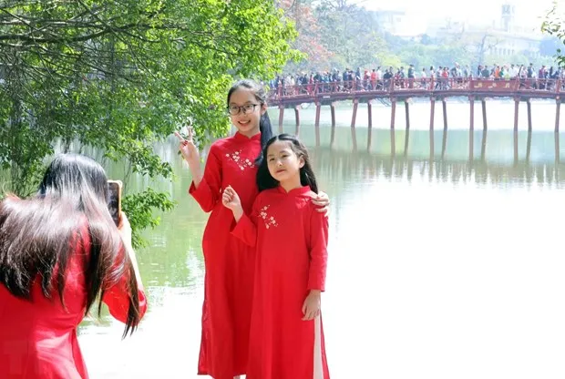 People take a photo besides Hoan Kiem Lake in Hanoi on February 11, the second day of the Year of the Dragon. (Photo: VNA)