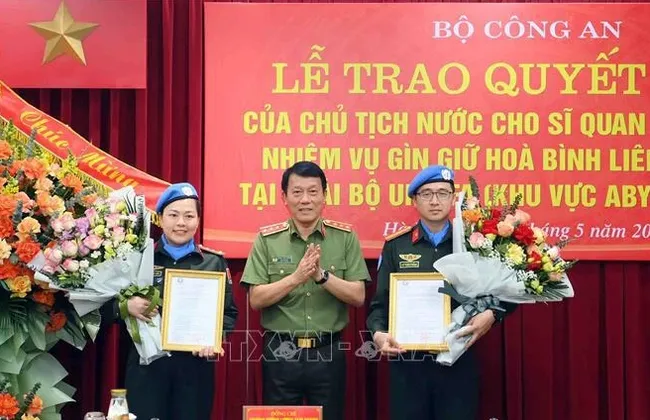 Deputy Minister of Public Security Sen. Lt. Gen. Luong Tam Quang (centre) presents the State President's decisions to the two officers on May 29. (Photo: VNA)