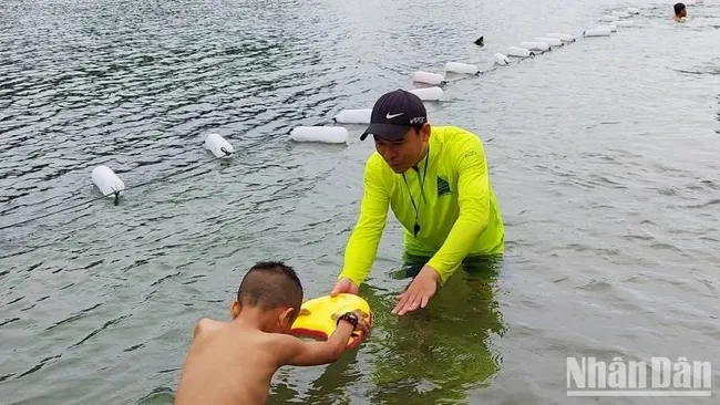 A technician from Chua Me Dat Tourism Company teaches swimming to children in Phong Nha Town, Quang Binh. (Photo: NDO)