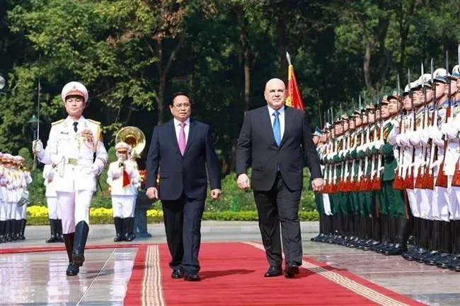 Prime Minister Pham Minh Chinh (L) and Russian Prime Minister Mikhail Vladimirovich Mishustin review the honour guard of the Vietnam People's Army at the official welcome ceremony. (Photo: VNA)