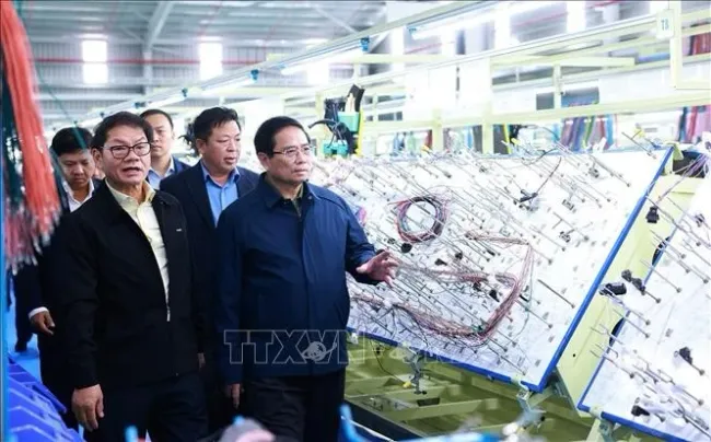 Prime Minister Pham Minh Chinh (R) visits the production line of THACO Group. (Photo: VNA)
