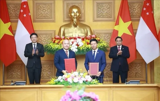 Prime Minister Pham Minh Chinh (R) and Singaporean Prime Minister Lawrence Wong (L) witness the exchange of the cooperation agreement between the Vietnam-Singapore Friendship Association and the Singapore International Foundation. (Photo: VNA)