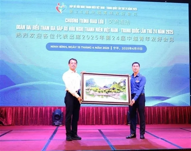 Secretary of the Ninh Binh provincial Youth Union Trinh Nhu Lam (right) presents a painting of the Trang An landscape to a representative of the Chinese youth. (Photo: VNA)