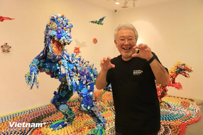 Artist Hiroshi Fuji poses in front of his works at the exhibition