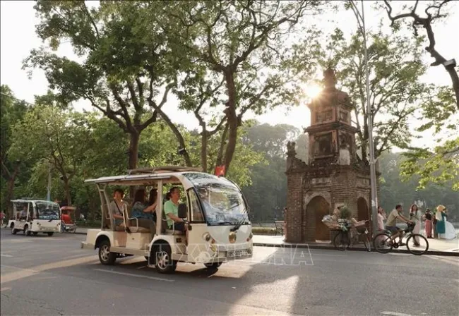 Tourists travel around Hoan Kiem Lake by electric cars. (Photo: VNA)