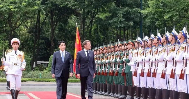 State President Luong Cuong (left) and French President Emmanuel Macron review the Guard of Honour of the Viet Nam People’s Army. (Photo: VNA)