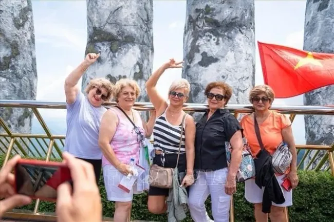 Foreign tourists enjoy checking in on the Golden Bridge in the Sun World Ba Na Hills complex in the central city of Da Nang. (Photo: VNA)