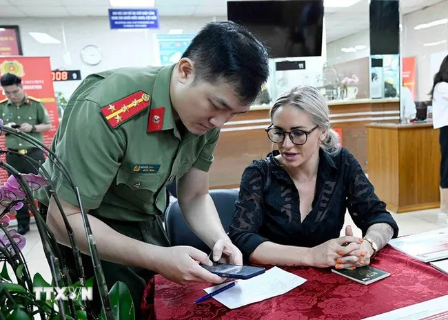 A police officer instructs a foreigner how to register for a level-2 electronic identification account. (Photo: VNA)