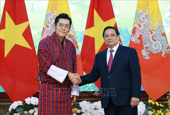 Prime Minister Pham Minh Chinh (R) welcomes King of Bhutan Jigme Khesar Namgyel Wangchuck in Hanoi on August 19. (Photo: VNA)
