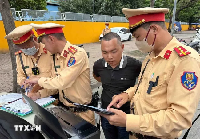 Traffic police officers present image evidence of a violation to a driver. (Photo: VNA)